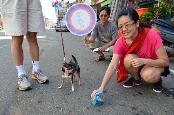 可愛狗寵物店老闆娘曾雅萍，在世界無車日走路預演中，示範「遛狗不留便、隨手清狗便」。（柏原祥攝）