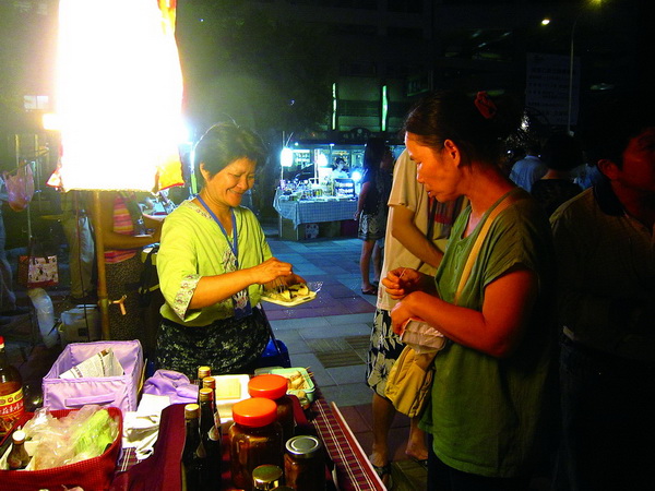 老闆娘吳美慧在指紋市集中，請顧客品嘗擁有懷舊好滋味的花生豆腐。(林子婷攝)